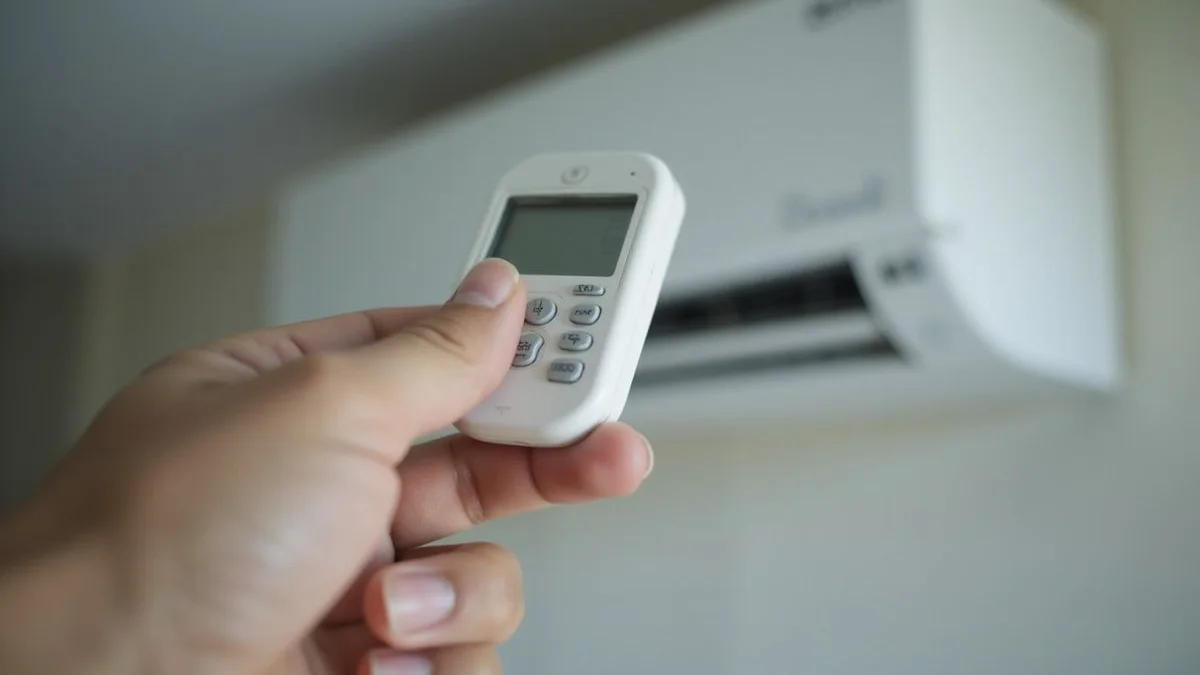 Close-up comic pop-art illustration of a hand pressing buttons on an aircon remote control